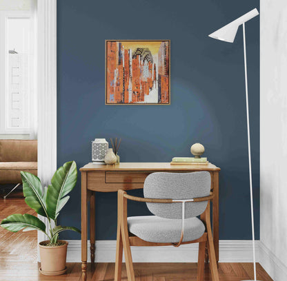 Home office with wooden desk, gray chair, and abstract art on a blue wall.