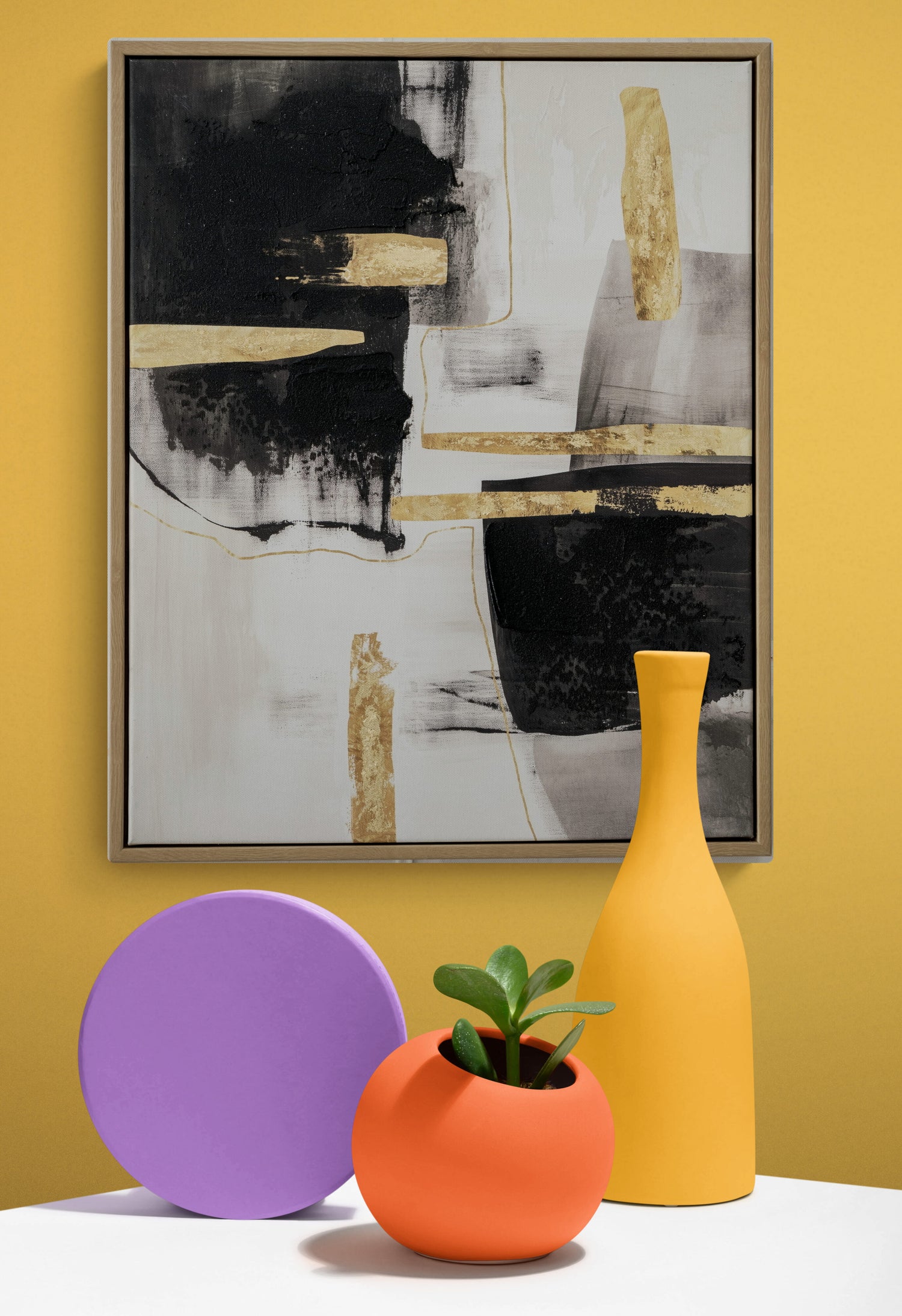 Abstract art piece on a yellow wall with colorful decor items below.
