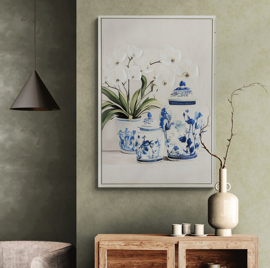 Framed artwork of blue and white ceramic jars with plants on a wall above a wooden console table.