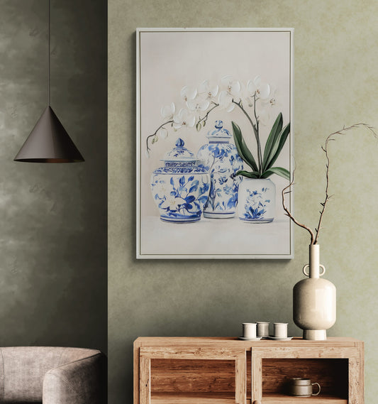 Framed artwork of blue and white ceramic jars on a green wall above a wooden console table.