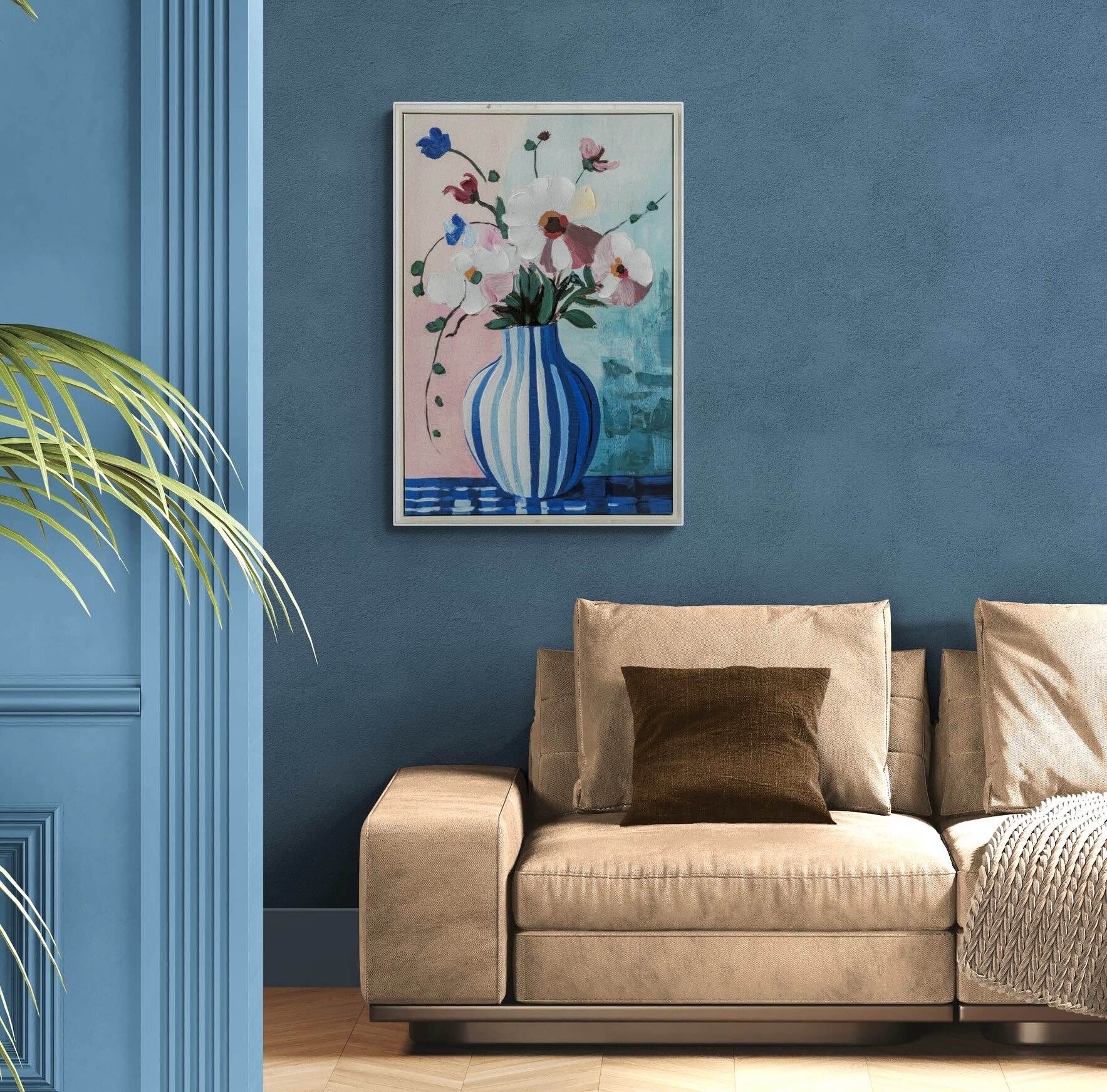 Beige sofa with a brown pillow against a blue wall with a floral painting.