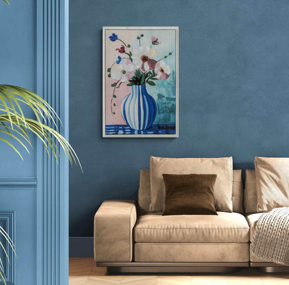 Beige sofa with a brown pillow against a blue wall with a floral painting.