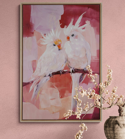 Framed artwork of two cockatoos on a branch against a pink background, with a vase and branches in the foreground.